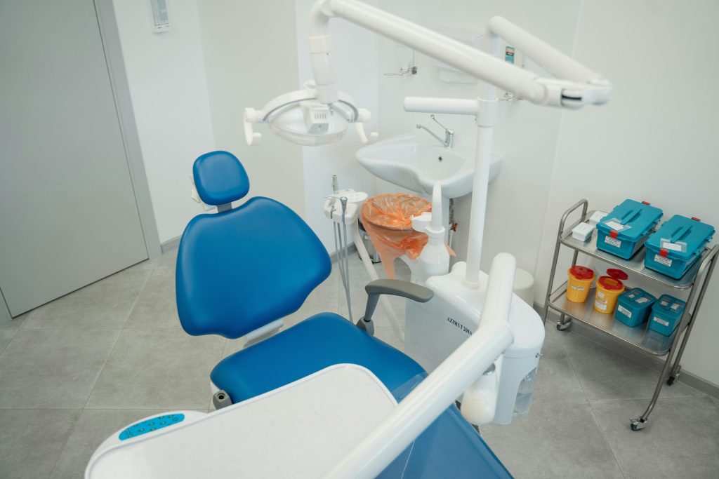 A clean and modern dental clinic featuring a blue dental chair, equipment, and sterile supplies.